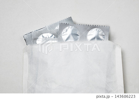 Silver blister packs of pills spilling out of a white paper pharmacy bag on a light background. Silver blister packs of pills spilling out of a white paper pharmacy bag on a light background. 143686223