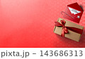 Christmas composition with a craft gift box tied with a red ribbon and an envelope with a Merry Christmas card on a red background. Concept of Merry Christmas 143686313