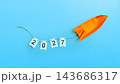 An orange origami rocket launches upward, towing a string of flags spelling the year 2027 against a vibrant blue background, symbolizing future growth, goals, and ambition. Concept of Happy New Year 143686317