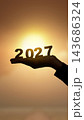 Silhouette of a hand holding the year 2027 against a bright sunset background, representing the future, new beginnings, and time passing. Concept of Happy New Year 143686324