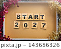 Start 2027 spelled out with wooden letter and number tiles inside a festive box decorated with pink and gold tinsel, top-down view. Concept of Happy New Year 143686326