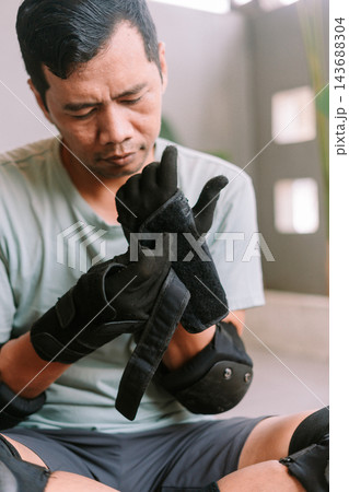 Person preparing for roller skating by putting on protective gear Person preparing for roller skating by putting on protective gear 143688304