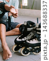 Person preparing protective gear before inline skating outdoors 143688337