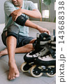 Person preparing protective gear before inline skating outdoors 143688338
