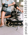 Person preparing protective gear and inline skates for outdoor sport 143688340