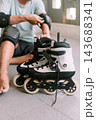 Person preparing inline skates with protective gear for outdoor recreation 143688341