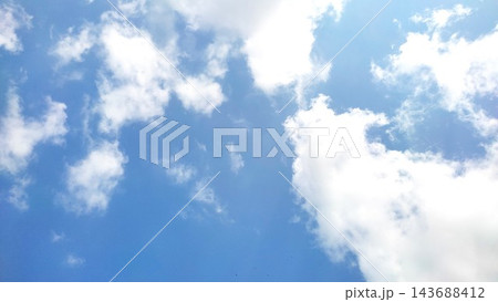 Bright Blue Sky With Fluffy White Clouds and Sunlight Glare 143688412