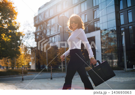 Pretty Businesswoman Walking In City Street With Black Bag Wearing Sunglasses And Stylish Outfit. Corporate Fashion Lifestyle Concept Female Professional 143693063