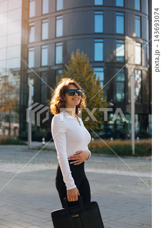 Beautiful Businesswoman Standing In City Holding Black Handbag Wearing Stylish Outfit And Sunglasses. Corporate Fashion Lifestyle Concept Female Professional 143693074
