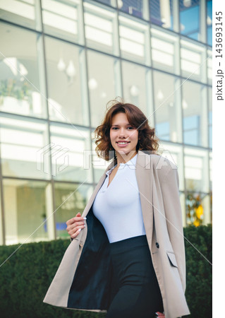 Attractive woman walking confidently in elegant business blazer outdoors. Beautiful woman enjoying modern corporate lifestyle near office. Career success concept. Attractive woman walking confidently in elegant business blazer outdoors. Beautiful woman enjoying modern corporate lifestyle near office. Career success concept. 143693145