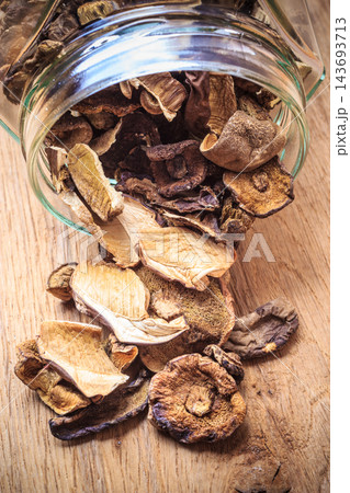 Dry mushrooms in jar on wooden table. 143693713