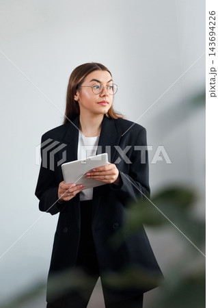 Attractive Business Woman Holding Tablet and Thinking in Office. Corporate Workplace and Planning Concept Attractive Business Woman Holding Tablet and Thinking in Office. Corporate Workplace and Planning Concept 143694226
