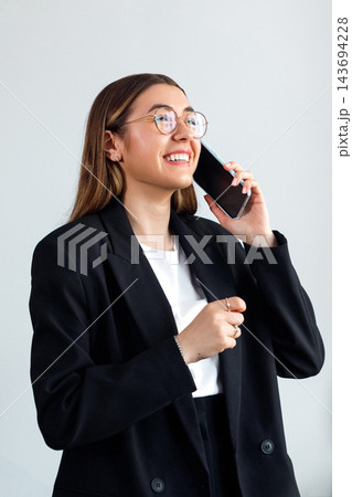 Beautiful Business Woman Talking on Smartphone and Smiling in Office. Corporate Workplace and Communication Concept 143694228