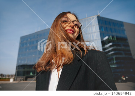 Attractive Business Woman Portrait With Wind In Hair Near Modern Office Building Wearing Black Blazer. Corporate Lifestyle Concept Female Professional Urban Attractive Business Woman Portrait With Wind In Hair Near Modern Office Building Wearing Black Blazer. Corporate Lifestyle Concept Female Professional Urban 143694942