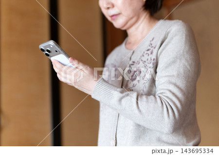 家でスマホを見るミドル・シニア女性 143695334