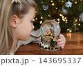 Christmas nativity snow globe captivates little girl during family celebrations 143695337