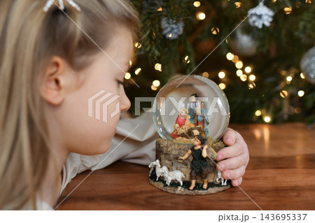 Christmas nativity snow globe captivates little girl during family celebrations 143695337