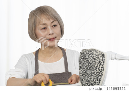リビングで趣味のDIYでドールチェアーをリメイクするシニア女性 リビングで趣味のDIYでドールチェアーをリメイクするシニア女性 143695521