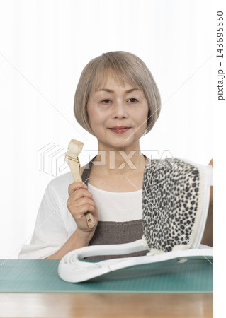 リビングで趣味のDIYでドールチェアーをリメイクするシニア女性 143695550