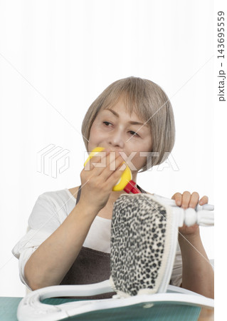 リビングで趣味のDIYでドールチェアーをリメイクするシニア女性 リビングで趣味のDIYでドールチェアーをリメイクするシニア女性 143695559