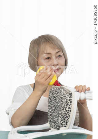 リビングで趣味のDIYでドールチェアーをリメイクするシニア女性 リビングで趣味のDIYでドールチェアーをリメイクするシニア女性 143695560