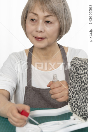 リビングで趣味のDIYでドールチェアーをリメイクするシニア女性 143695568