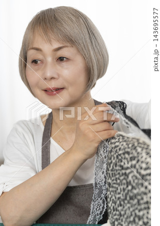 リビングで趣味のDIYでドールチェアーをリメイクするシニア女性 143695577