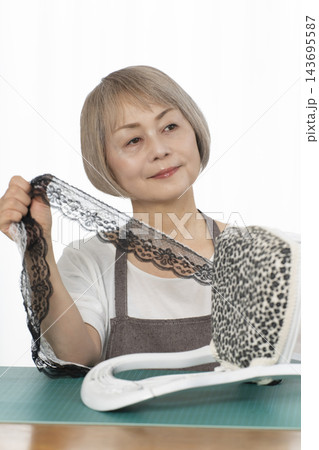 リビングで趣味のDIYでドールチェアーをリメイクするシニア女性 リビングで趣味のDIYでドールチェアーをリメイクするシニア女性 143695587