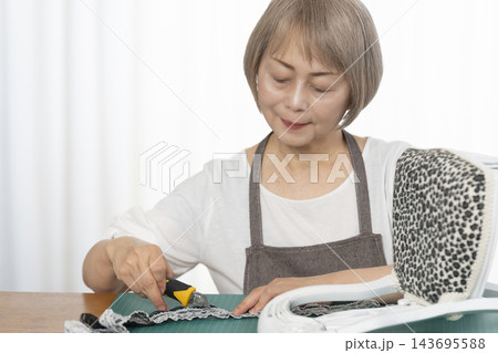 リビングで趣味のDIYでドールチェアーをリメイクするシニア女性 リビングで趣味のDIYでドールチェアーをリメイクするシニア女性 143695588