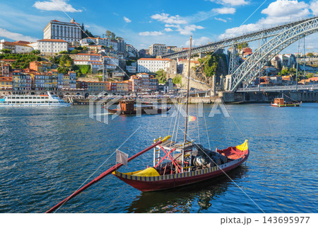 Rabelo boat moored near Porto Ribeira, Portugal, on the Douro River with wine barrels and Vila Nova de Gaia cityscape 143695977