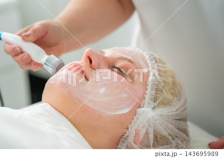 A professional care session in a beauty salon features a woman, ultrasonic facial, the face, facial device, an esthetician, and a skin treatment during a professional skincare session A professional care session in a beauty salon features a woman, ultrasonic facial, the face, facial device, an esthetician, and a skin treatment during a professional skincare session 143695989