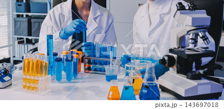 Medical or scientific researcher or man doctor looking at a test tube of clear solution in a laboratory 143697018