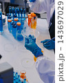 Medical or scientific researcher or man doctor looking at a test tube of clear solution in a laboratory 143697029