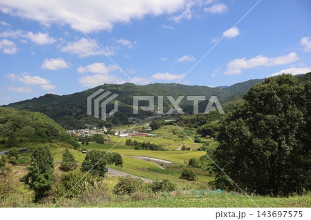 青空と白い雲と山と棚田とビニールハウスと民家や道のある村の風景 143697575