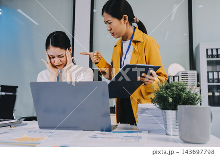 Two Asian businesswomen are facing stress and headache at the office, feeling exhausted from work pressure, focusing on mental health and stress management in a stressful corporate environment. Two Asian businesswomen are facing stress and headache at the office, feeling exhausted from work pressure, focusing on mental health and stress management in a stressful corporate environment. 143697798