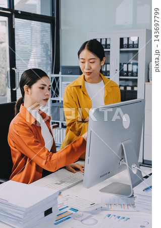 Two Asian business women looking at tablet and working together in office workspace. Two Asian business women looking at tablet and working together in office workspace. 143697799
