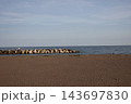 波紋の砂浜の海岸とテトラポットの防波堤と青い海面の海と水平線と白い薄雲と青空の風景 143697830