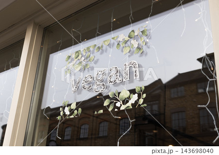 Vegan sign with decorative leaves in a glass shop window Vegan sign with decorative leaves in a glass shop window 143698040