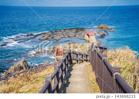 「青森県」荒々しい岩礁に架かる朱塗りの橋と快晴の海岸風景　高野埼 143698233