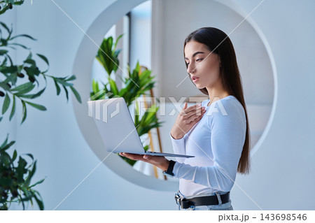 Young female student video calling or presenting on laptop in modern campus setting Young female student video calling or presenting on laptop in modern campus setting 143698546