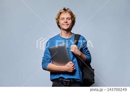 Smiling teenage student boy with backpack and textbook notebook against grey background 143700249