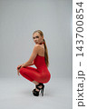 Woman in sheer red dress crouching and looking over shoulder 143700854