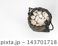 Overhead view of an open gray velvet drawstring pouch sack revealing smooth white pebble stones inside, isolated on white background, conceptual image of mystery, hidden treasure, surprise 143701718