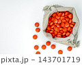 Flat lay top view of open beige fabric drawstring pouch filled with bright orange round medicine tablets, several pills scattered on clean white background, pharmaceutical healthcare and mystery 143701719