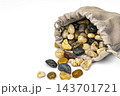 Close-up of a beige suede drawstring bag tipped over with assorted polished river stones in white, yellow, brown and black tumbling out, conceptual image of mystery, hidden value, risk and surprise 143701721