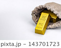 Glittering 999.9 fine gold bullion bars weighing 200 grams each spilling from an opened gray suede drawstring pouch on clean white background, concept of unknown contents revealed as valuable treasure 143701723
