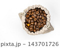 Overhead flat lay of aromatic dark roasted arabica coffee beans discovered inside an opened rustic beige linen drawstring sack, symbolizing surprise and hidden value, isolated on clean white 143701726