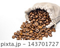Close-up of glossy fresh roasted arabica coffee beans spilling generously from an opened beige fabric drawstring pouch, revealing its hidden valuable contents, isolated on a bright white studio 143701727