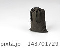 Concept of mystery and uncertainty shown by a small black fabric drawstring pouch tightly tied closed, hiding unknown contents that could be precious treasure or completely worthless, isolated 143701729