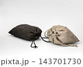 Mystery and uncertainty concept showing two closed drawstring pouches made of soft black and beige suede fabric, tightly tied with cords and hiding unknown contents that may be highly valuable 143701730